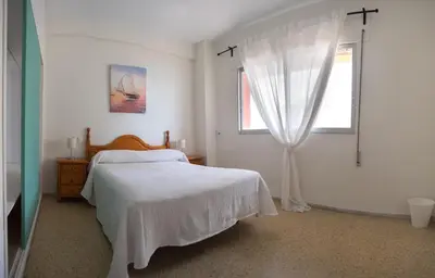 a white bedroom with a bed and a window at Delfín Playa Basic Ha Apartment in Cádiz