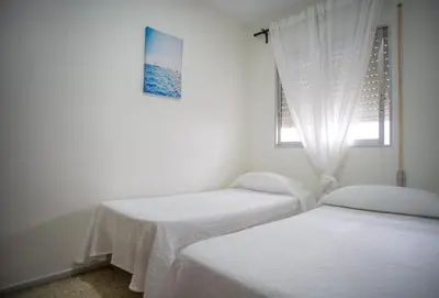 two beds in a white room with a window at Delfín Playa Basic Ha Apartment in Cádiz