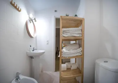 a bathroom with a shelf with towels and a sink at Delfín Playa Basic Ha Apartment in Cádiz