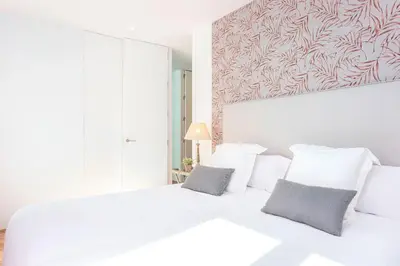 a white bedroom with a large white bed with two pillows at Genteel Home San Antonio in Cádiz