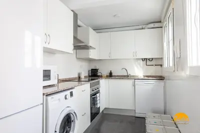 a kitchen with white cabinets and a washer and dryer at Apartamento Vintage by Cadiz Time in Cádiz