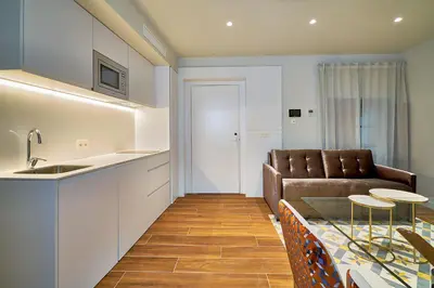 a kitchen and living room with a couch and a table at Tandem Torres de Cádiz Suites in Cádiz