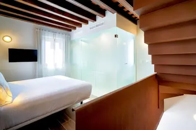 a bedroom with a bed and a glass wall at Tandem Torres de Cádiz Suites in Cádiz