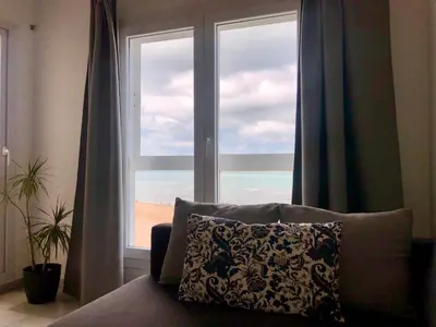 a couch with a pillow in front of a window at GATU Vista Infinita 1ªlinea mar WIFI, AIRE ACC, TERRAZA CON VISTAS in Cádiz