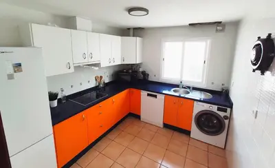 a kitchen with orange and white cabinets and a washing machine at El ático de los flamencos, Apartamentos Living Sur in Sanlúcar de Barrameda