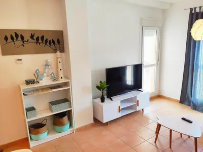 a living room with a tv and a table at El ático de los flamencos, Apartamentos Living Sur in Sanlúcar de Barrameda