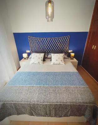 a bedroom with a large bed with a blue wall at El ático de los flamencos, Apartamentos Living Sur in Sanlúcar de Barrameda