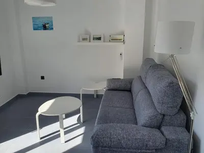 a living room with a blue couch and a table at Apartamento Campoamor in Sanlúcar de Barrameda
