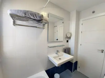 a white bathroom with a sink and a mirror at Apartamento Campoamor in Sanlúcar de Barrameda