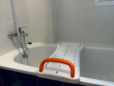 a white bath tub with an orange chair sitting on it at Apartamento Campoamor in Sanlúcar de Barrameda