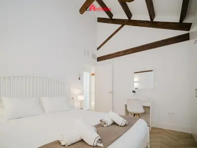 a bedroom with a white bed with two towels on it at DUPLEX NUEVO CONVENTO PLAZA CABILDO in Sanlúcar de Barrameda