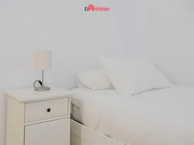 a white bedroom with a white bed and a nightstand at DUPLEX NUEVO CONVENTO PLAZA CABILDO in Sanlúcar de Barrameda