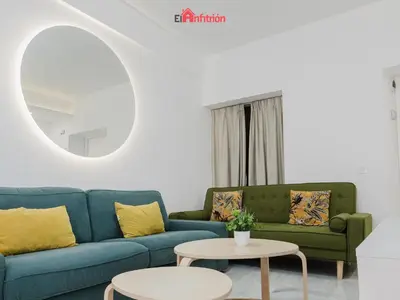 a living room with a blue couch and a table at DUPLEX NUEVO CONVENTO PLAZA CABILDO in Sanlúcar de Barrameda
