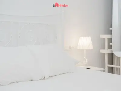 a white bedroom with a white bed and a lamp at DUPLEX NUEVO CONVENTO PLAZA CABILDO in Sanlúcar de Barrameda