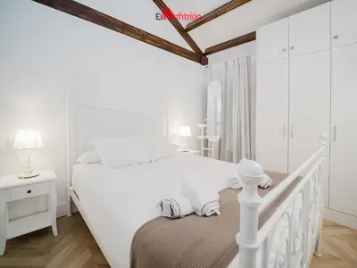 a white bedroom with a white bed and a window at DUPLEX NUEVO CONVENTO PLAZA CABILDO in Sanlúcar de Barrameda