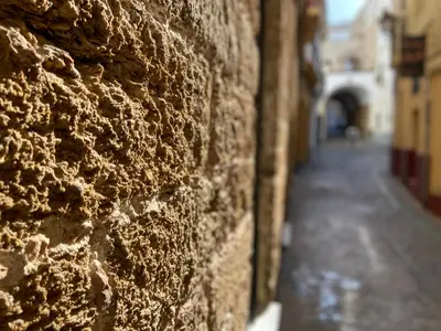 a stone wall with an alley in the distance at GADEIRAS SUITES - Apartamentos Turísticos de 2 llaves in Cádiz