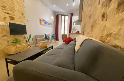 a living room with a gray couch and a stone wall at GADEIRAS SUITES - Apartamentos Turísticos de 2 llaves in Cádiz