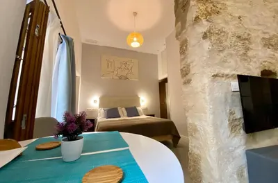 a living room with a bed and a table with a tv at GADEIRAS SUITES - Apartamentos Turísticos de 2 llaves in Cádiz
