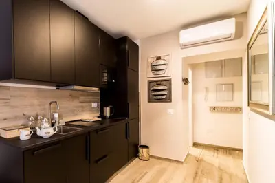 a kitchen with black cabinets and a wooden floor at Suite Capitán 1 in Cádiz