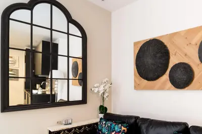 a living room with a black leather couch and a mirror at Suite Capitán 1 in Cádiz