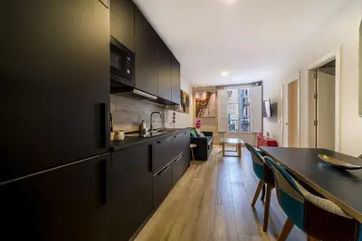 a kitchen with black cabinets and a dining table at Suite Capitán 2 in Cádiz