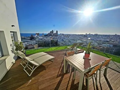 a wooden deck with a table and chairs on a balcony at Skyline - Penthouse with 50m2 private terrace and stunning views in Cádiz