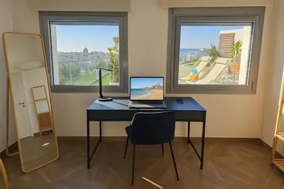 a desk with a laptop on it in a room with two windows at Skyline - Penthouse with 50m2 private terrace and stunning views in Cádiz