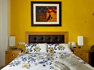 a bedroom with a bed with a yellow wall at Apartamento Esencia - Ole Solutions in Arcos de la Frontera