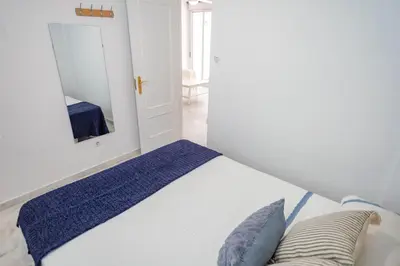 a bedroom with a white bed and a mirror at GINVA - Apartamento con terraza en la ribera del río in El Puerto de Santa María