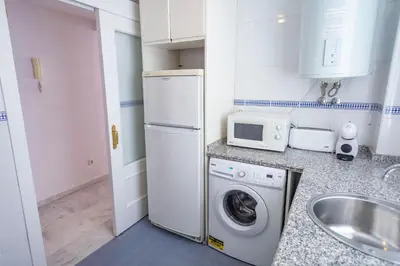 a small kitchen with a washing machine and a microwave at GINVA - Apartamento con terraza en la ribera del río in El Puerto de Santa María