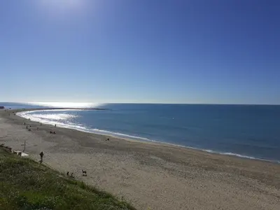 a beach with people walking on the sand and the ocean at Apartamento Puerta al Mar in Cádiz
