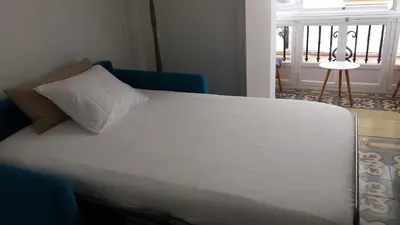 a white bed with a pillow on top of it at Los Balcones de Cádiz in Cádiz