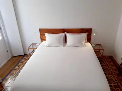 a bedroom with a large white bed with two tables at Los Balcones de Cádiz in Cádiz
