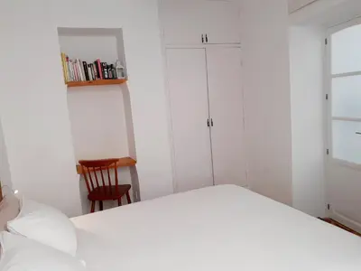a white bedroom with a bed and a chair at Los Balcones de Cádiz in Cádiz