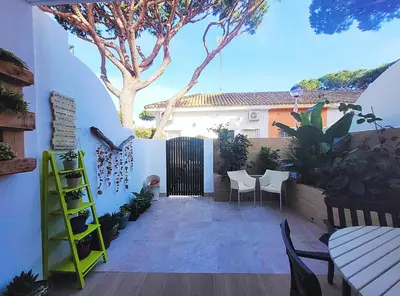 a patio with a table and chairs and a tree at Cozy Chalet - playa a 200m in Chiclana de la Frontera
