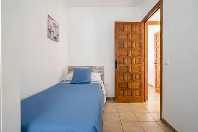 a bedroom with a blue bed and a door at Junto al Mar in Chiclana de la Frontera