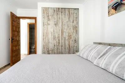 a white bedroom with a bed and a wooden door at Junto al Mar in Chiclana de la Frontera