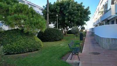 a bench sitting in the grass next to a building at Junto al Mar in Chiclana de la Frontera