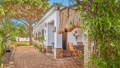 a white house with a table and chairs and trees at Villa Maymonis Chiclana de la Frontera by Ruralidays in Chiclana de la Frontera