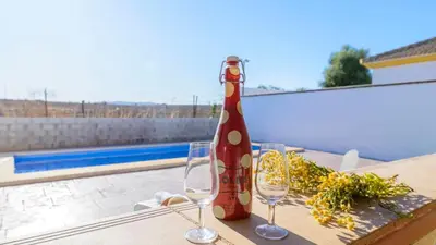 a red bottle sitting on a table with two wine glasses at Casa San Nicolas Algar by Ruralidays in Algar