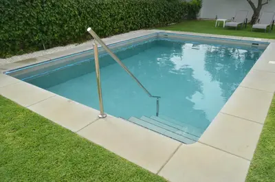 a swimming pool with two poles in the grass at EL ENCANTO Chiclana in Chiclana de la Frontera