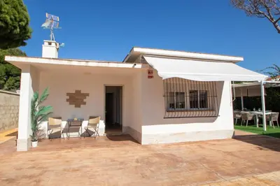 a white house with a patio and a white umbrella at EL ENCANTO Chiclana in Chiclana de la Frontera