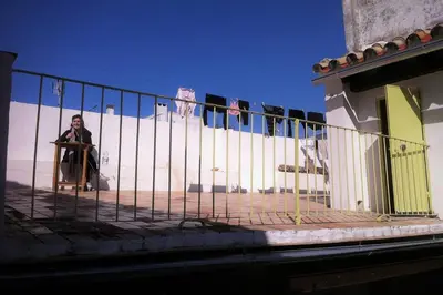 a man sitting in a chair behind a fence at Casa Florinda #7 in Jerez de la Frontera