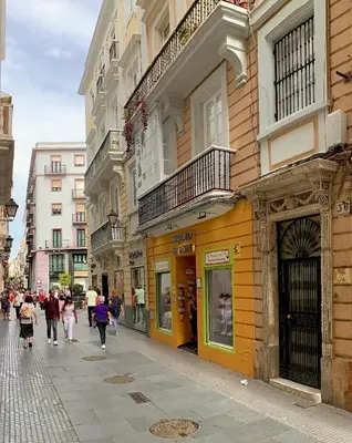 a group of people walking down a street next to buildings at Casa Maroca in Cádiz