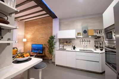 a kitchen with white cabinets and a table with a bowl of fruit at Casa Maroca in Cádiz