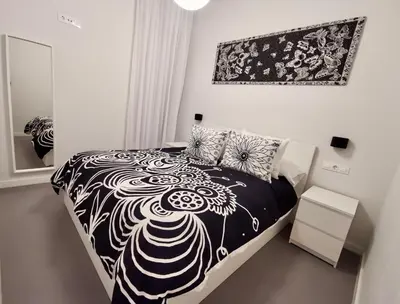 a black and white bed in a white bedroom at Casa Maroca in Cádiz