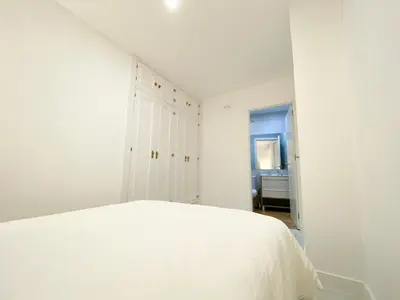 a white bedroom with a bed and a bathroom at apartamentos la reina in Arcos de la Frontera