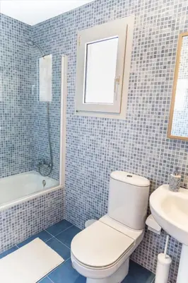 a blue tiled bathroom with a toilet and a sink at Estupendo Adosado Urbanizacion Hoyo 12 Novo Sancti Petri in Chiclana de la Frontera