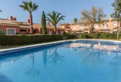 a large blue swimming pool with palm trees and houses at Estupendo Adosado Urbanizacion Hoyo 12 Novo Sancti Petri in Chiclana de la Frontera