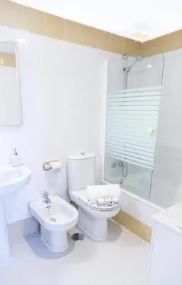 a white bathroom with a toilet and a sink at Estupendo Adosado Urbanizacion Hoyo 12 Novo Sancti Petri in Chiclana de la Frontera